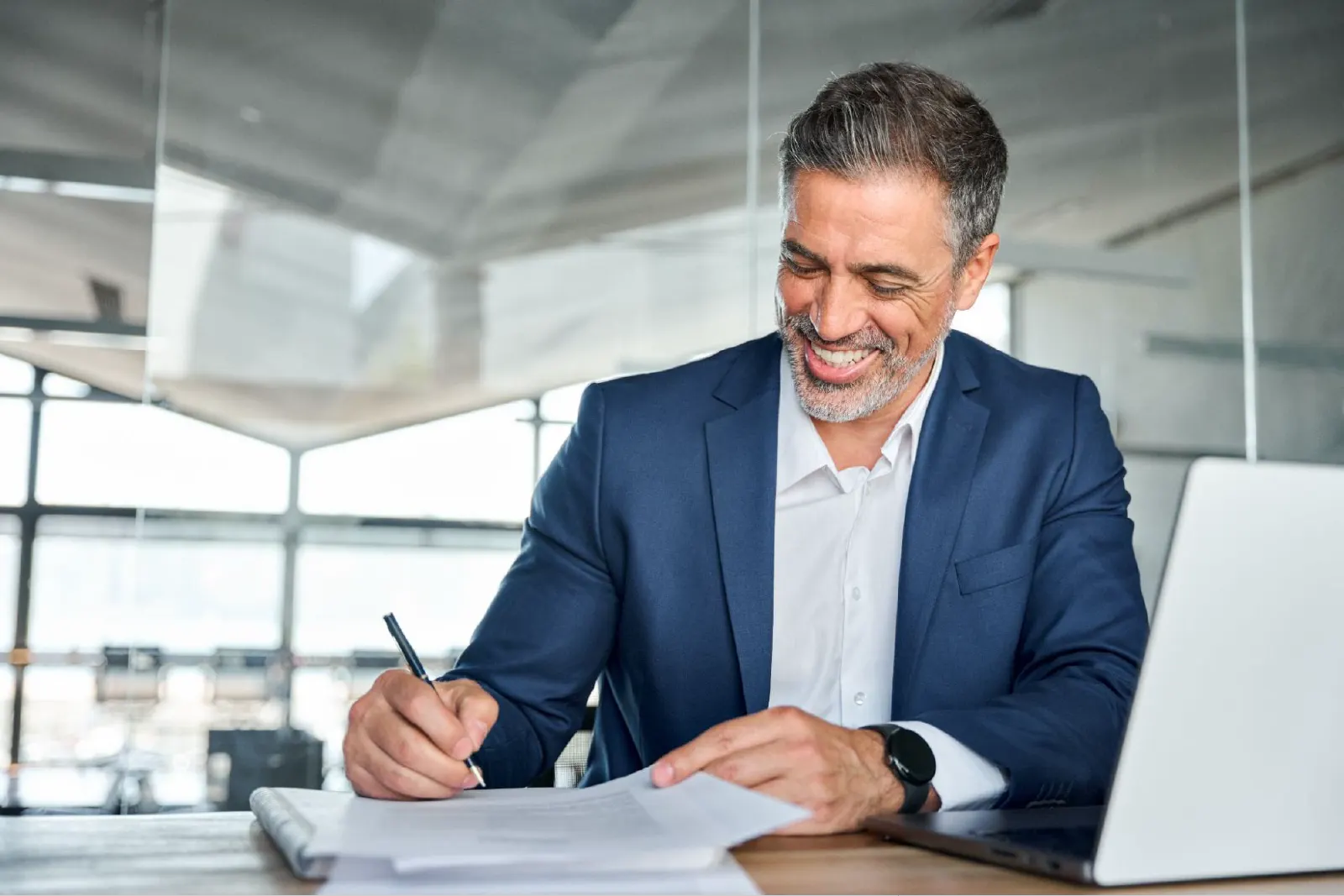 Hombre de negocios sonriente firmando un documento en una oficina